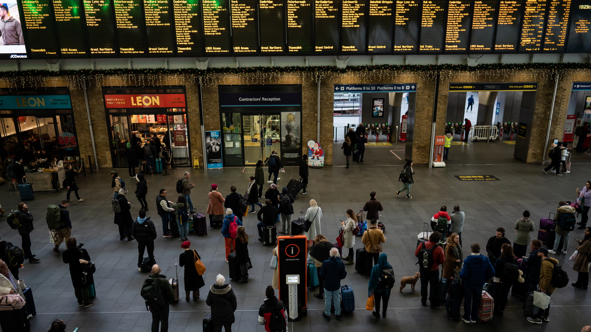Bahnreisende stehen am 24. Dezember vor Anzeigetafeln auf dem Londoner Bahnhof Kings Cross. | dpa