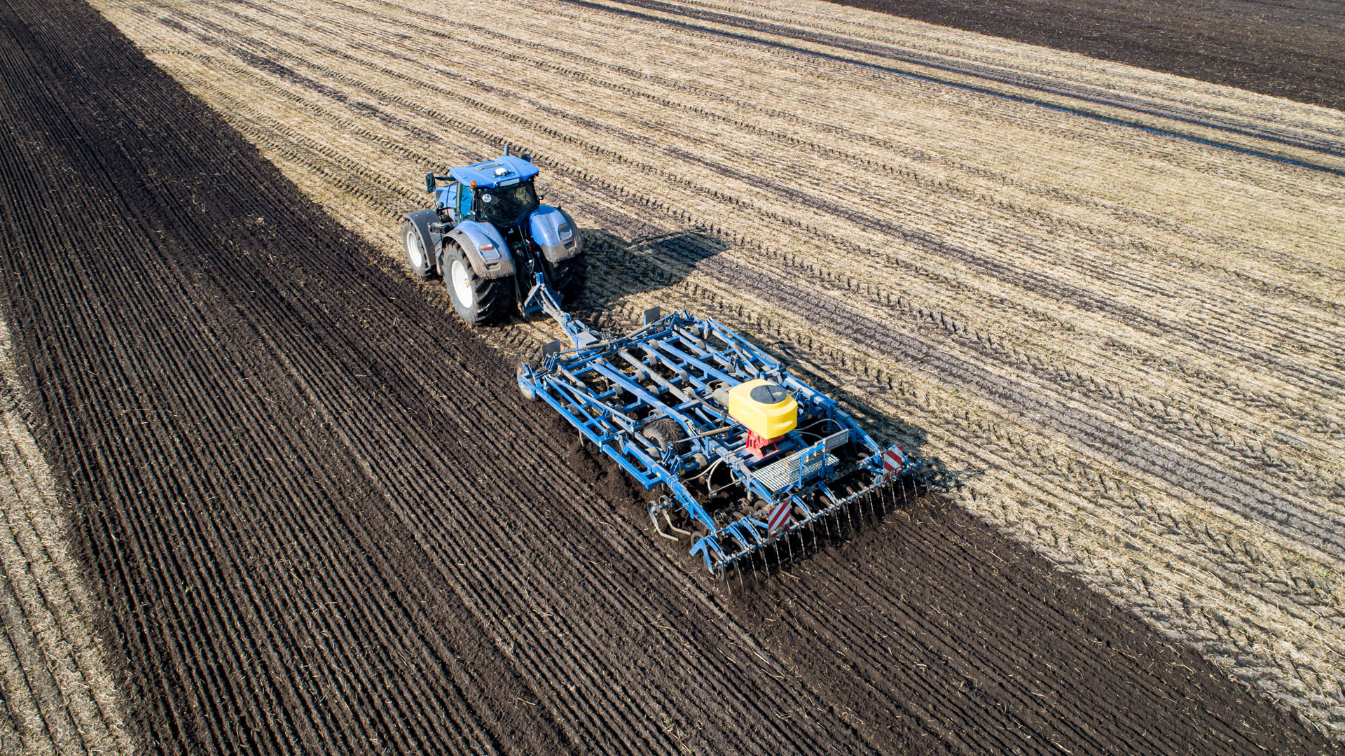 Traktor mit schwerem Grubber arbeitet Gülle in den Boden ein. | picture alliance / Countrypixel
