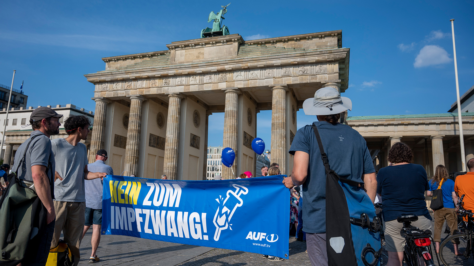Teilnehmer halten ein Plakat mit der Aufschrift «Nein zum Impfzwang» des österreichischen Senders AUF1 bei einer Kundgebung vor dem Brandenburger Tor in Berlin. | dpa