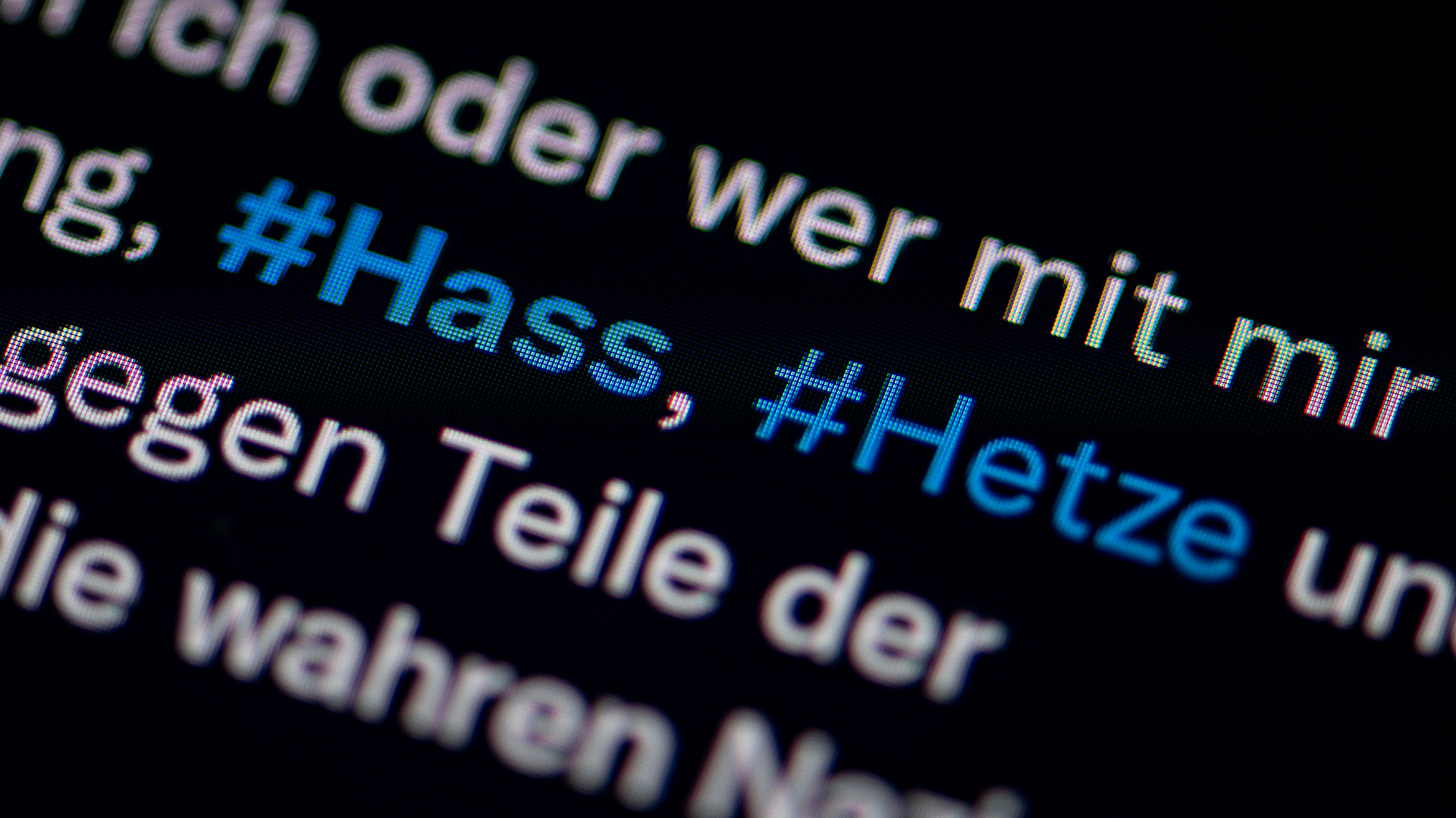 Auf dem Bildschirm eines Smartphones sieht man die Hashtags Hass und Hetze in einem Twitter-Post.  | dpa