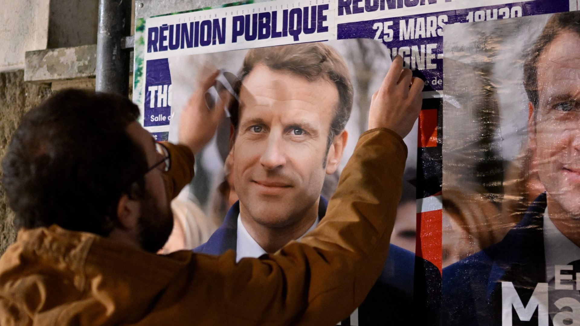 Ein Unterstützer von Frankreichs Präsident Macron hängt ein Wahlplakat auf | AFP