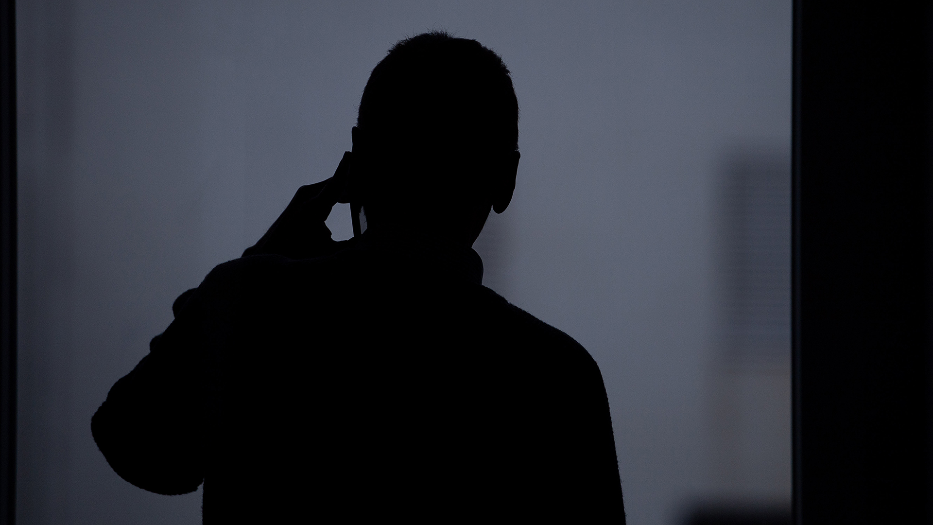 Die Silhouette eines Mannes, der mit einem Smartphone telefoniert. | picture alliance/dpa