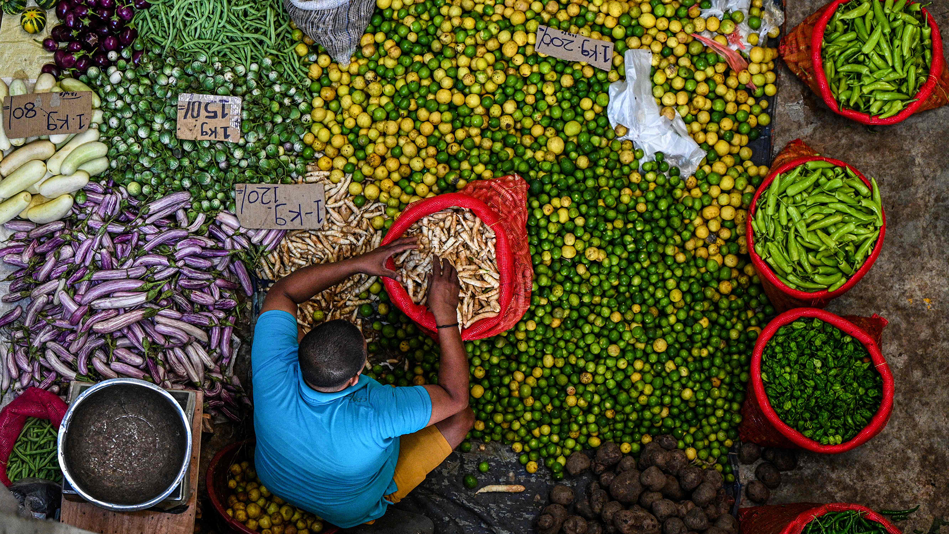 Ein Gemüseverkäufer sitzt umgeben von seine Waren auf dem Boden. | AFP