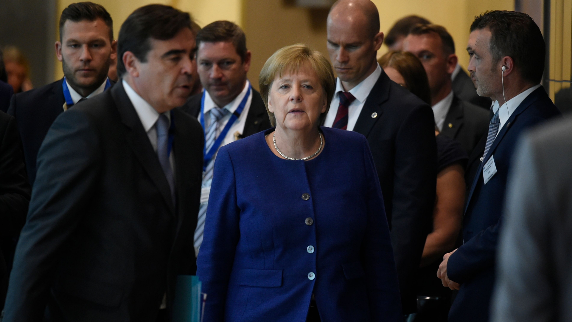 Bundeskanzlerin Merkel in Brüssel in einem Flur umgeben von Personen in Anzügen. | AFP