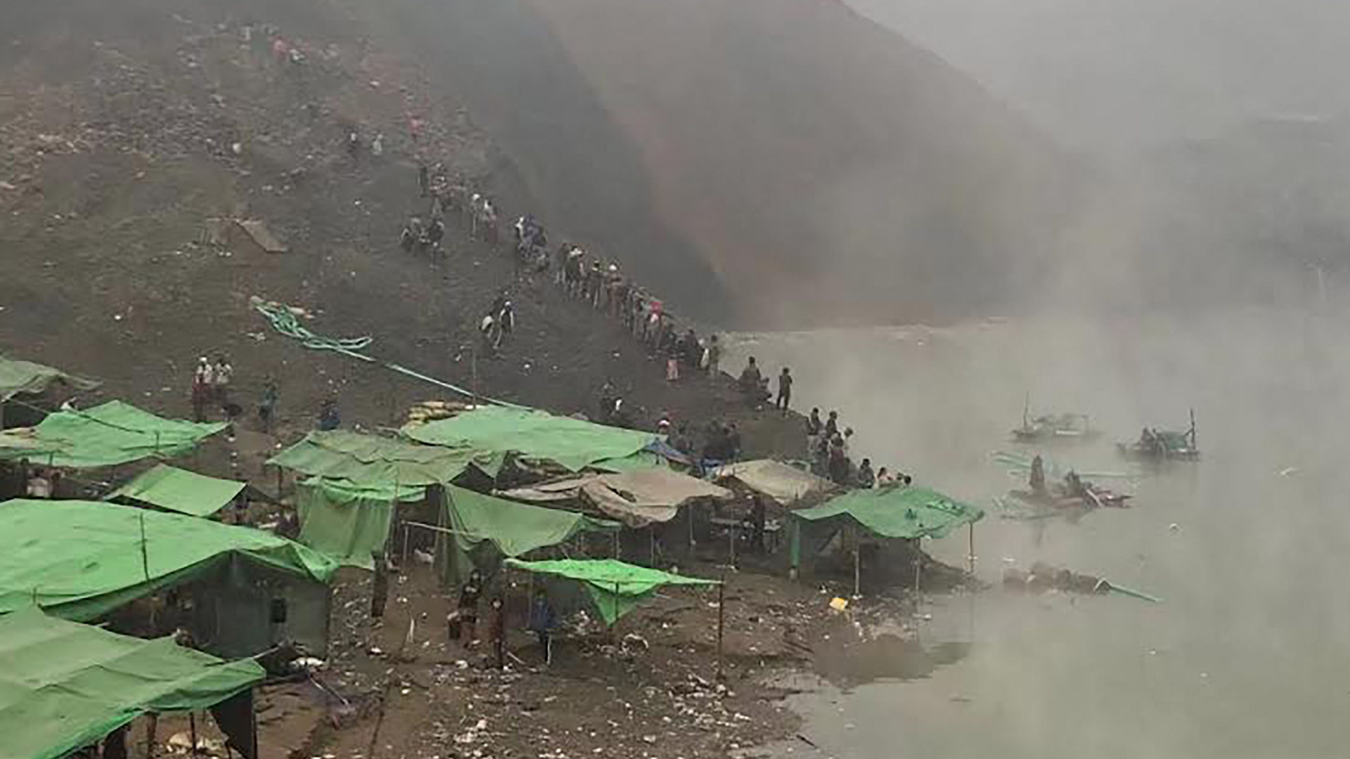 Nach einen Erdrutsche in einer Jade-Mine in Myanmar suchen Rettungskräfte mit Booten in einem See nach Vermissten. | AFP