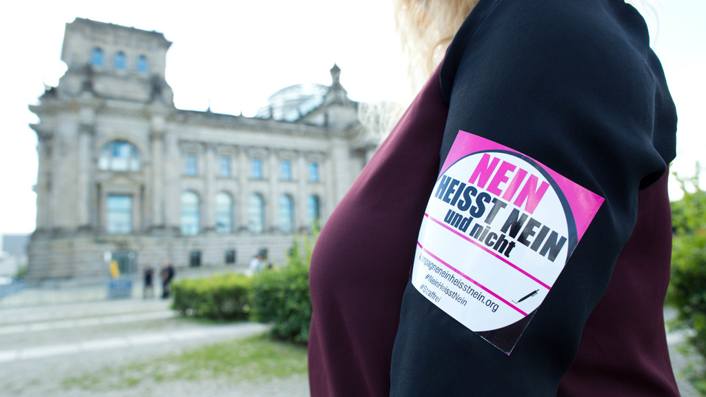 Eine Frau mit einem "Nein heißt Nein"-Aufkleber am Arm steht vor dem Reichstagsgebäude