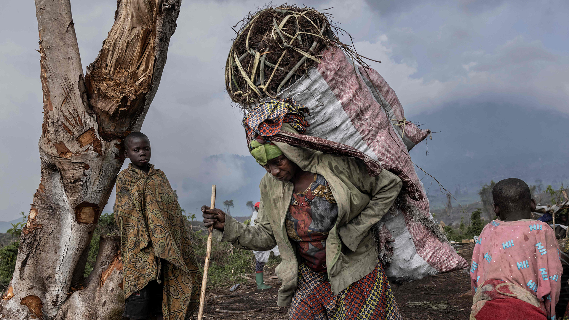 Eine Frau trägt einen Sack mit Holz auf ihrem Rücken. | AFP