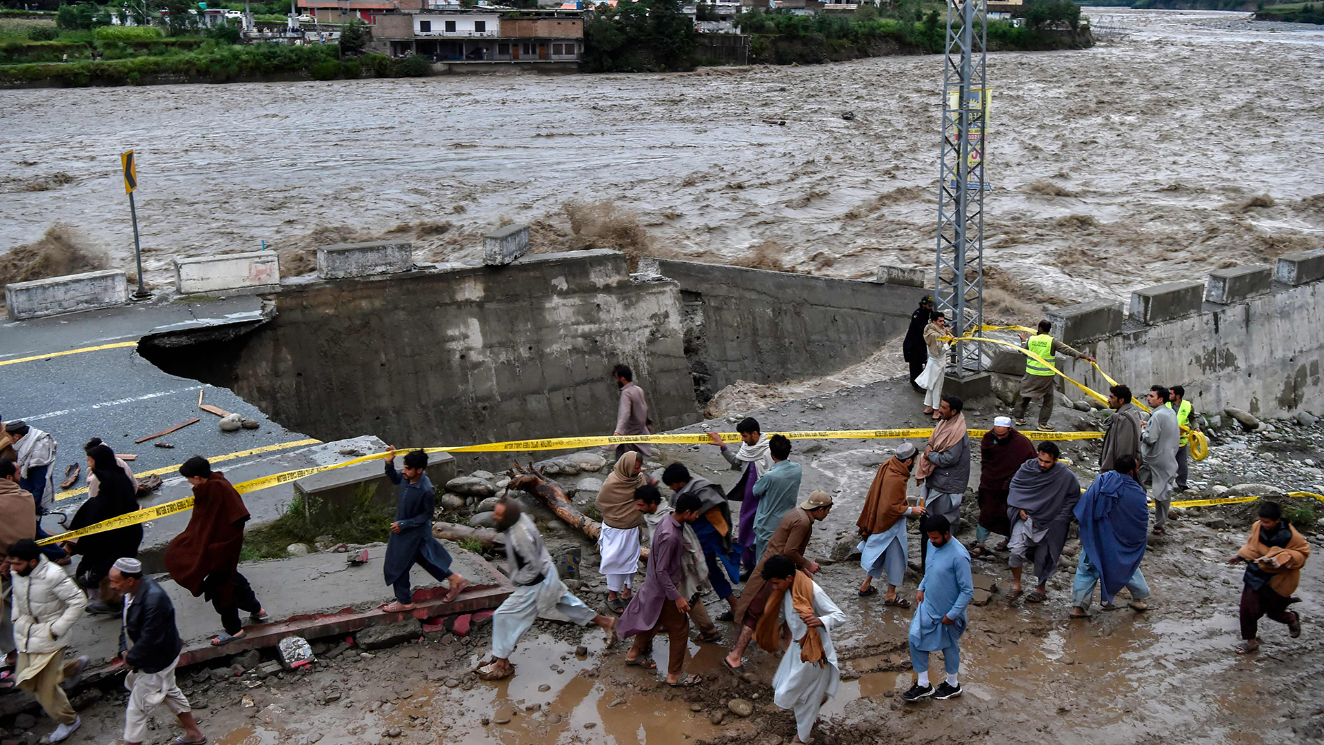 Menschen versammeln vor einer Straße,  die nach heftigen Monsunregen durch Hochwasser beschädigt wurde. | AFP