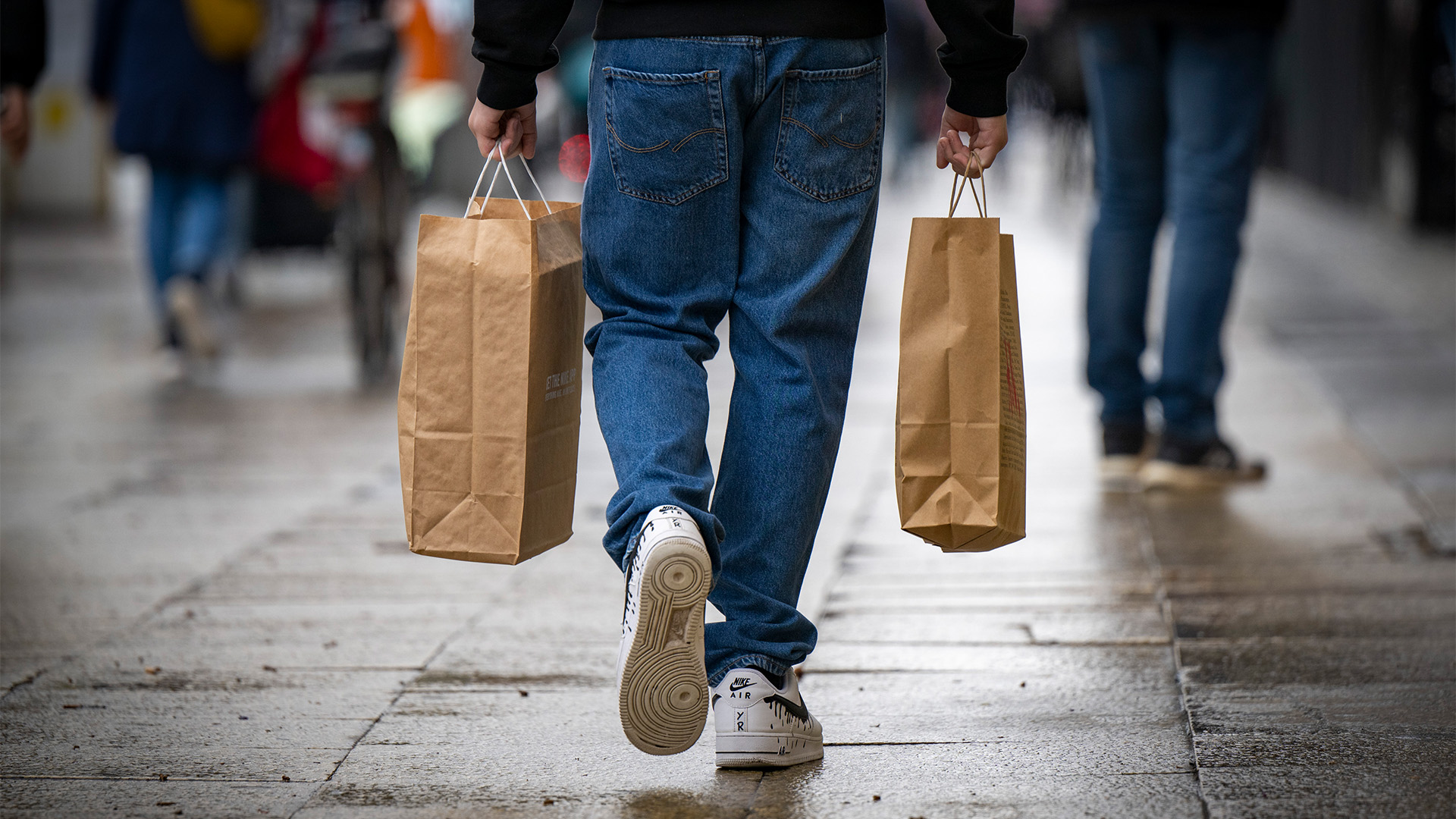 Ein Mann mit zwei Einkaufstaschen geht über eine Einkaufsstraße . | dpa