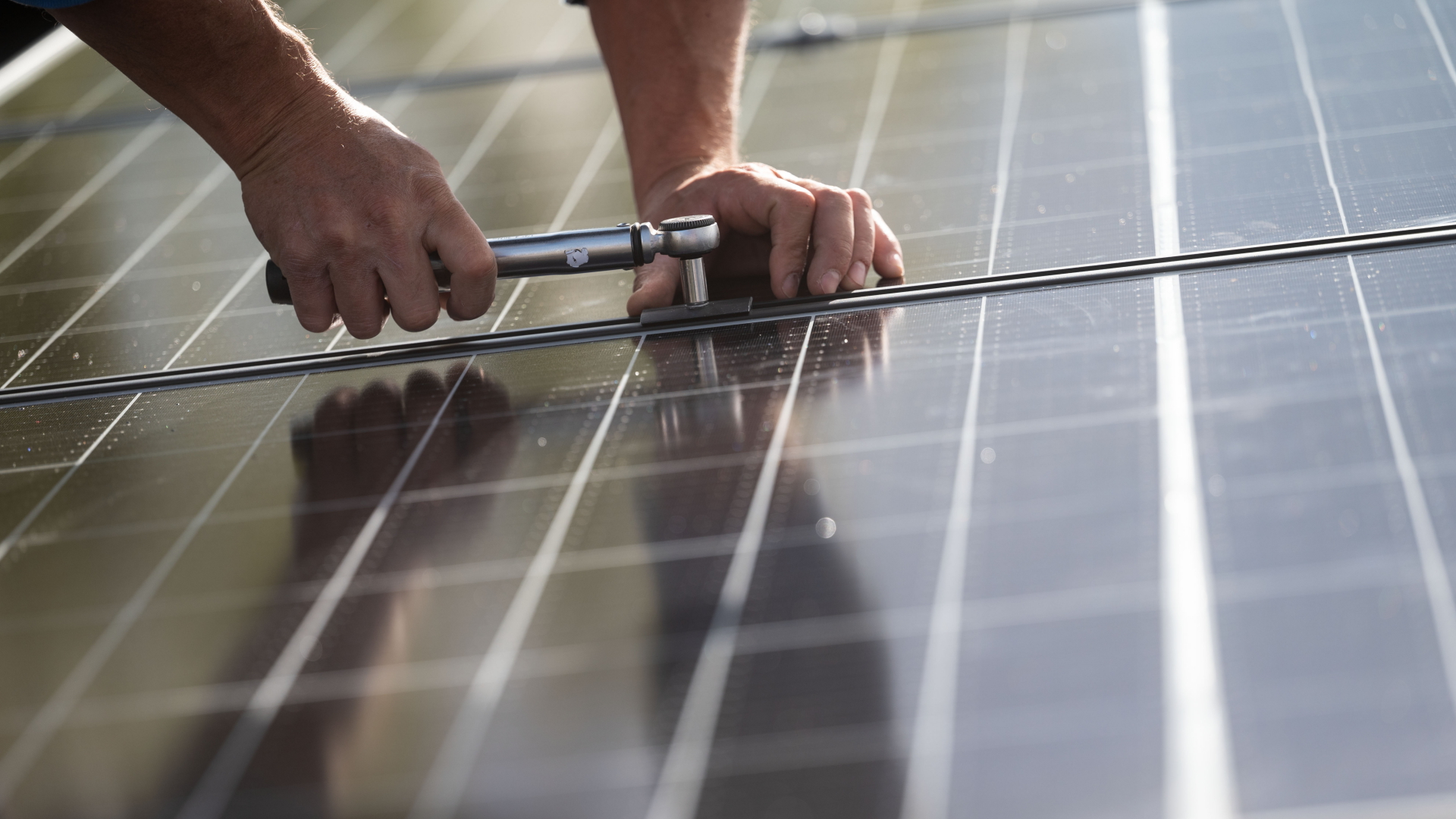Hände montieren eine Photovoltaikanlage auf einem Dach | dpa
