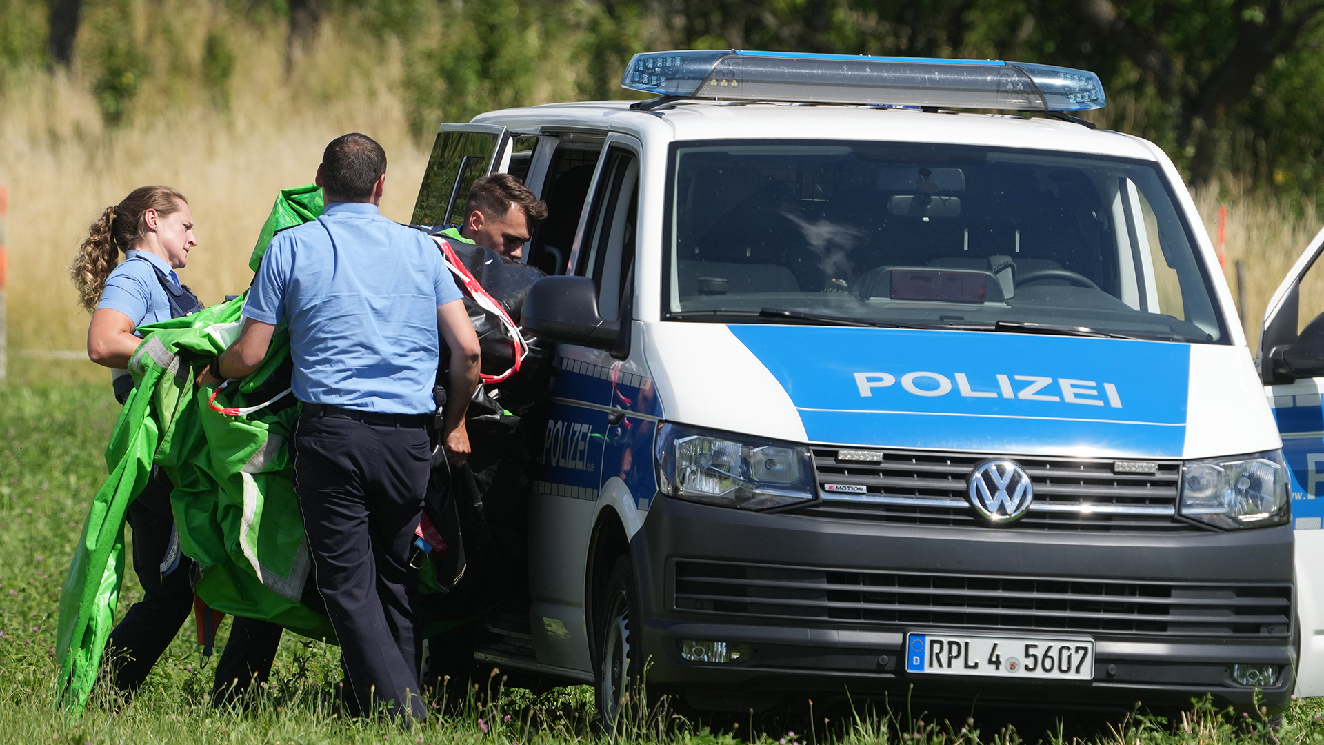  Polizeibeamte transportieren die Hülle einer Hüpfburg ab in einem VW-Bus der Polizei ab. | picture alliance/dpa