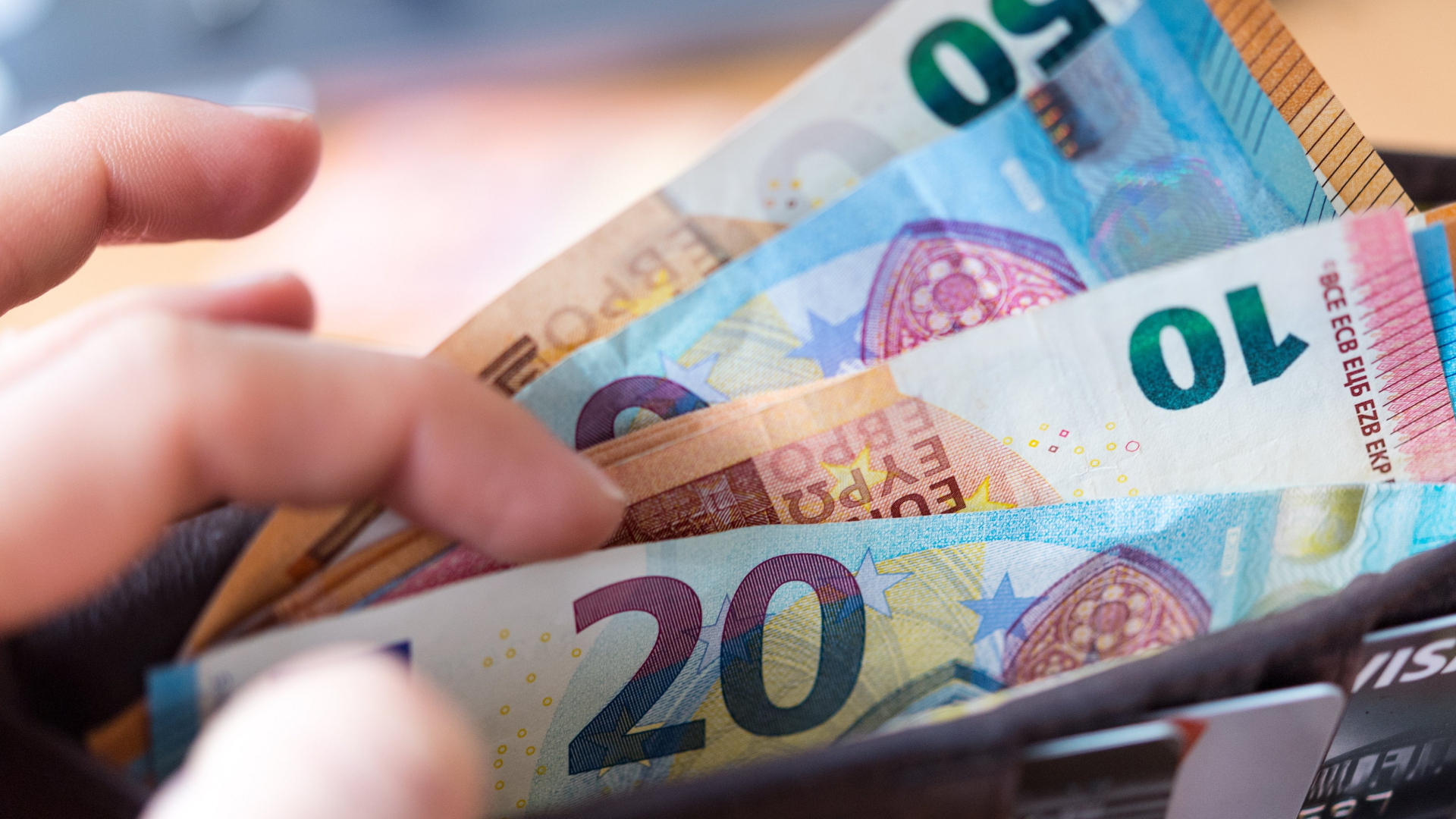 Eine Hand zieht Euroscheine aus einem Portemonnaie. | dpa