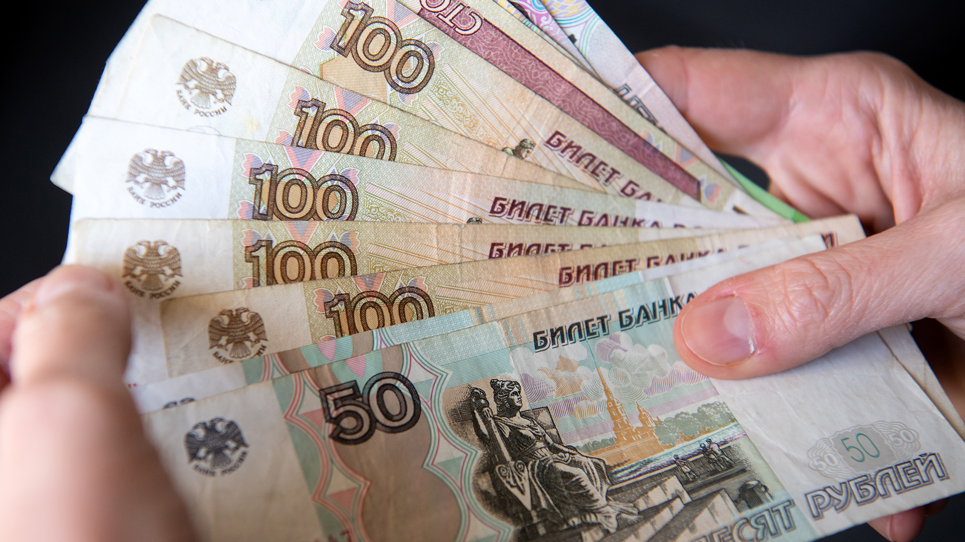 Ein weibliche Hand hält russische Rubel-Banknoten. | dpa