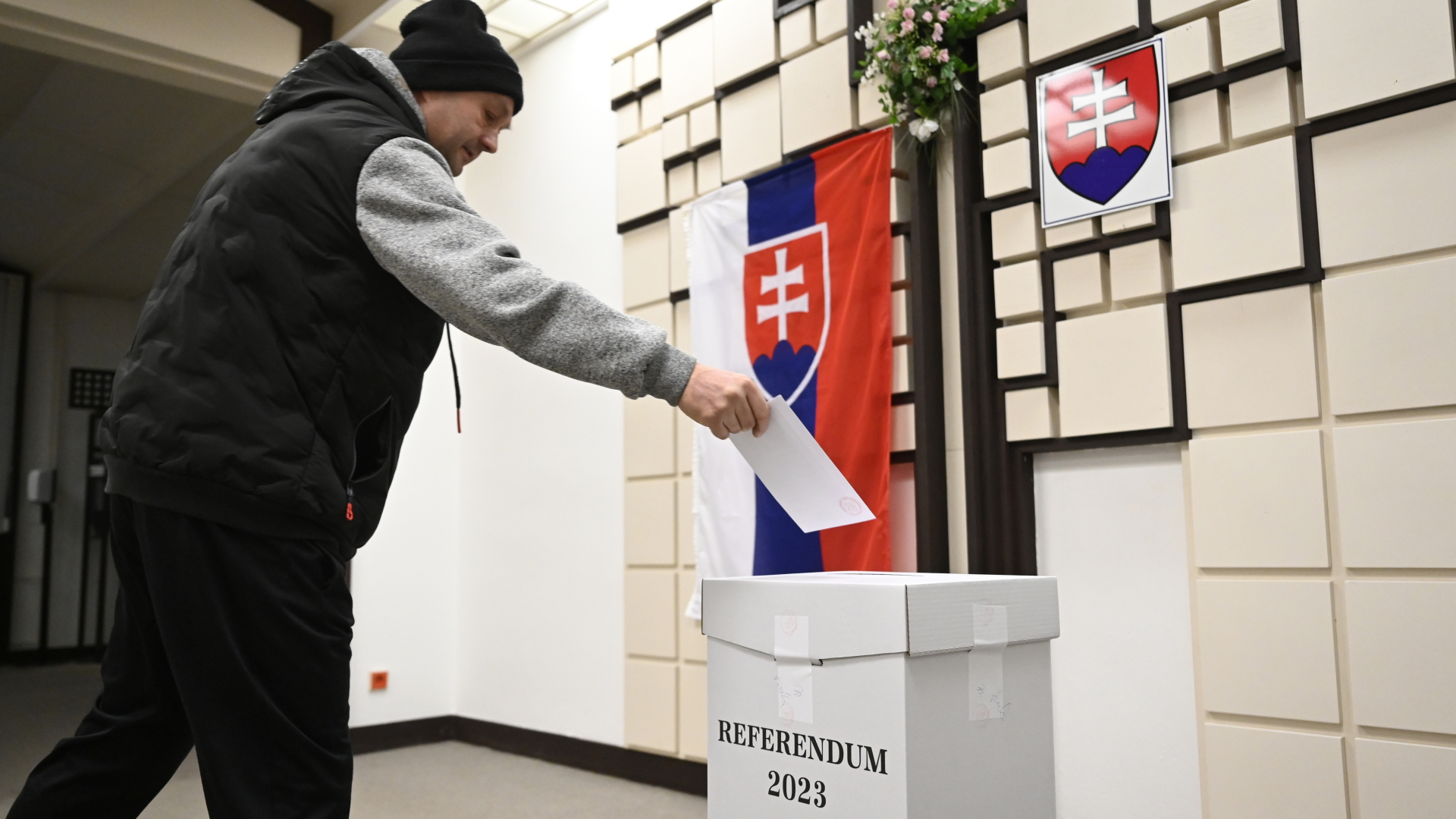 Ein Mann wirft seinen Wahlzettel zum Referendum über eine Verfassungsänderung in die Urne, dahinter hängt die slowakische Flagge. | dpa