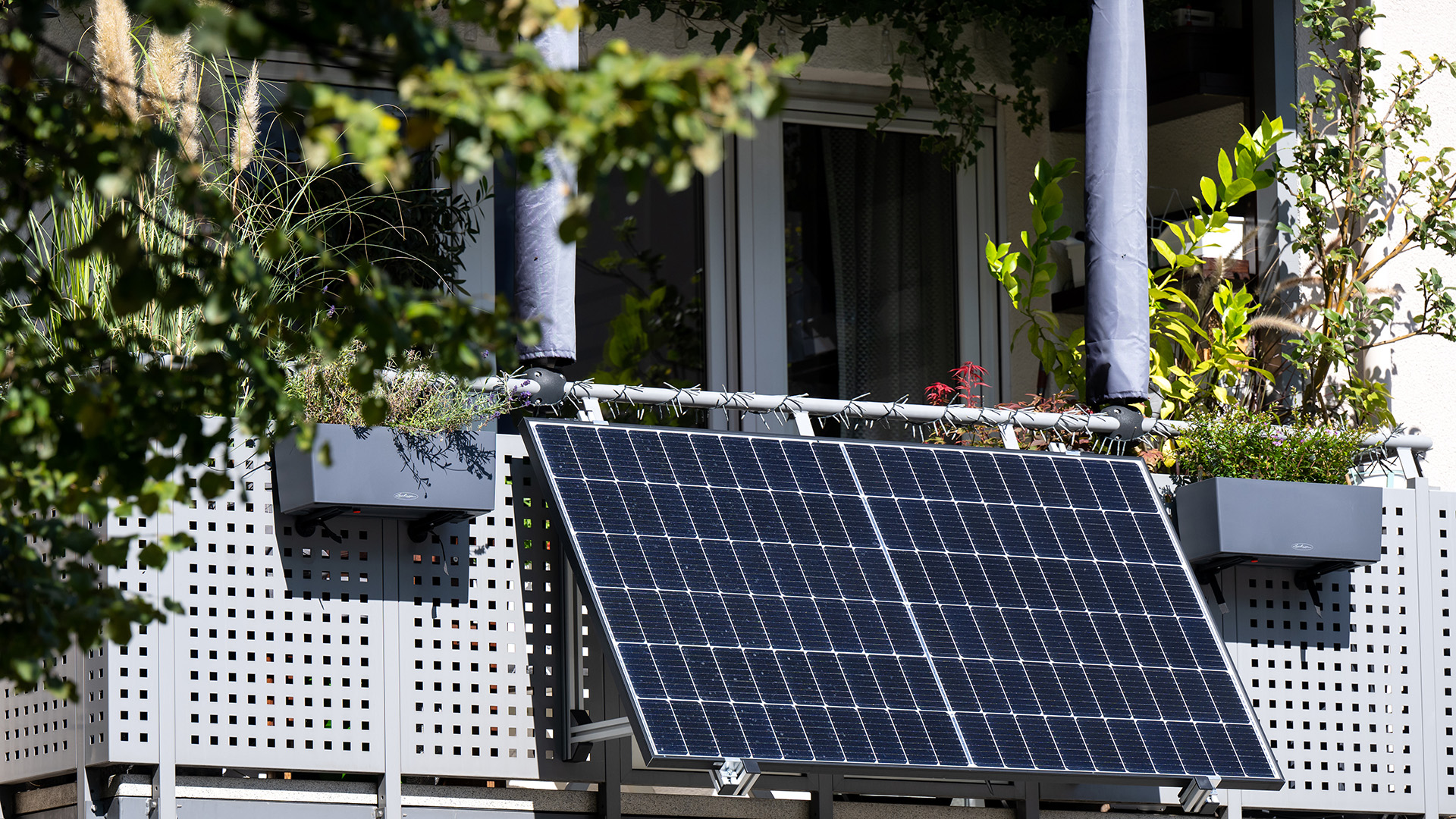 Eine kleine Solaranlage ist an einem Balkon eines Mehrparteienhauses angebracht. | picture alliance/dpa