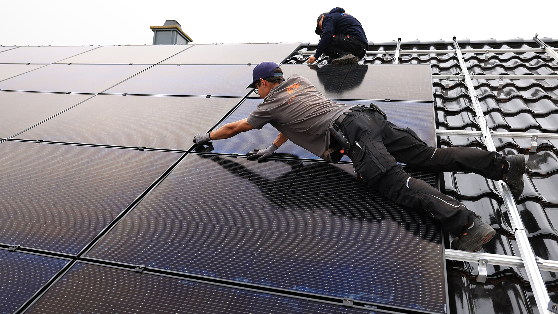 Handwerker montieren auf dem Dach eines Wohnhauses Solarmodule. | dpa