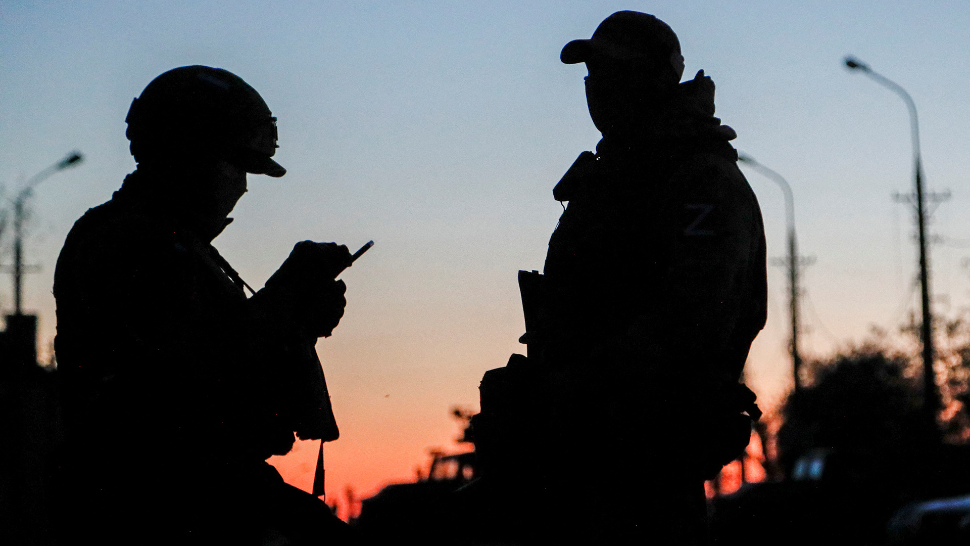 Russische Militärangehörige stehen bei Sonnenuntergang auf einer Straße in Mariupol (Ukraine) Wache. | REUTERS