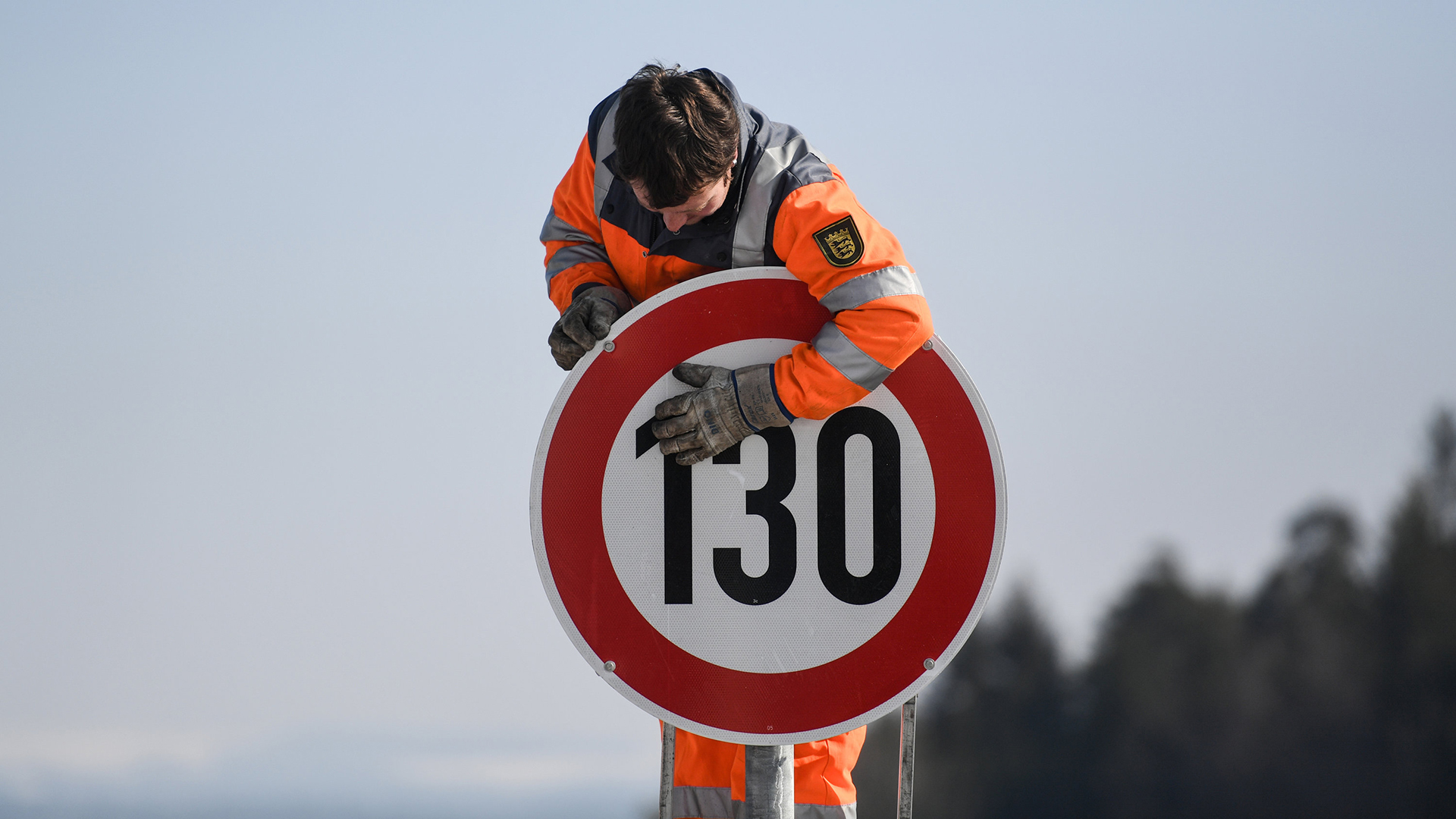 Ein Straßenwärter montiert an der Autobahn A81 am Hegaublick ein Schild mit der Aufschrift ''130''. | dpa