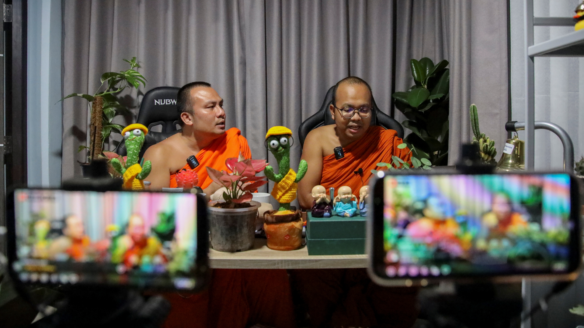 Die beiden buddhistischen Mönche Paiwan Warawanno und Sompong Talaputt beim Livestream vor den Handy-Kameras. | REUTERS