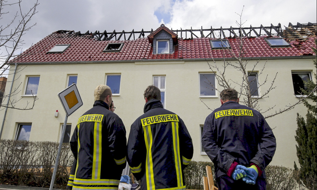 Feuerwehrleute vor einem durch einen Brand schwer beschädigtes Flüchtlingsheim in Tröglitz (April 2015)
