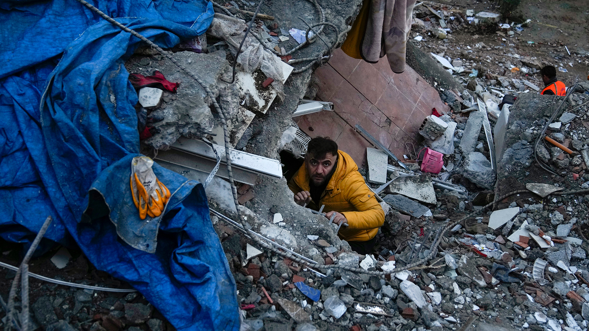Ein Mann sucht nach Menschen in einem zerstörten Gebäude in Adana (Türkei). | AP