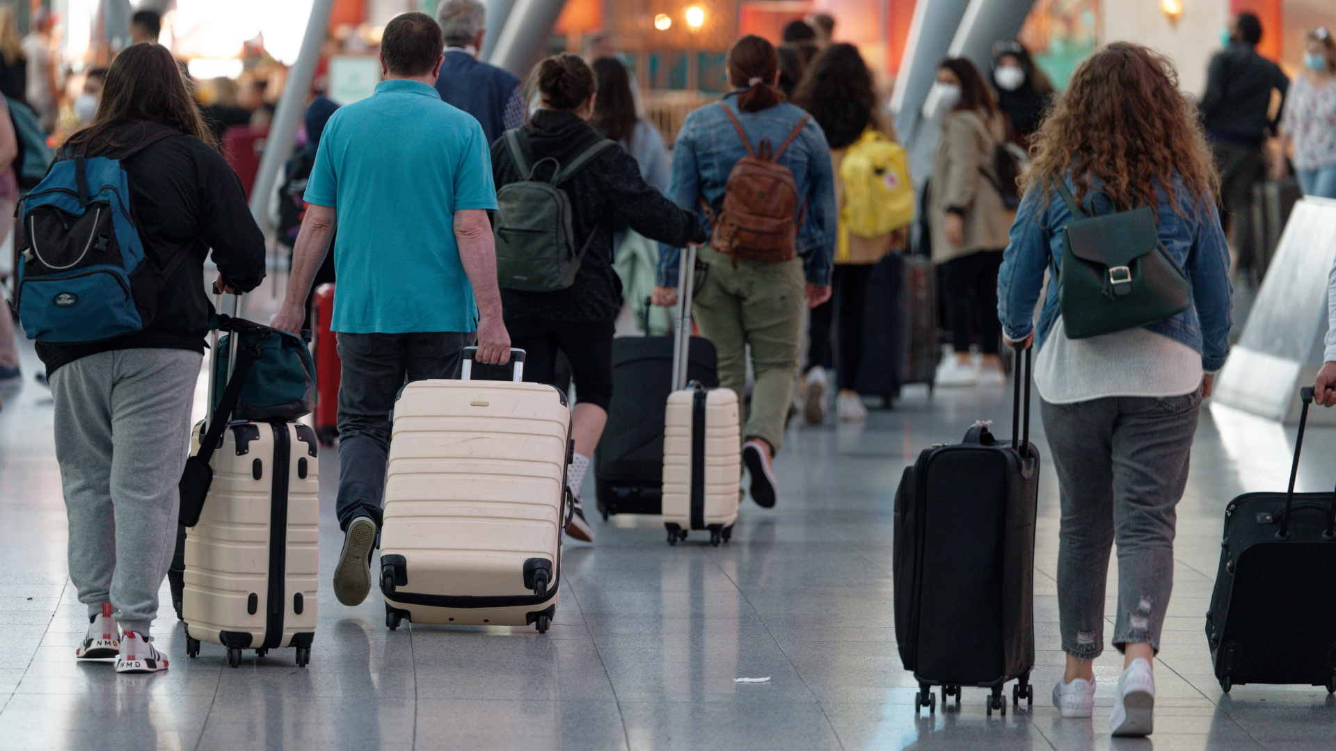 Reisende laufen mit ihren Koffern durch die Abflughalle des Flughafens in Düsseldorf, nachdem in Nordrhein-Westfalen Anfang Juni 2021 die Sommerferien gestartet sind. | dpa