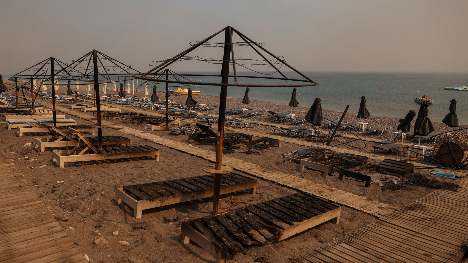 Vom Feuer zerstörte Sonnenschirme und Liegen an einer Strandbar in Vatera | REUTERS