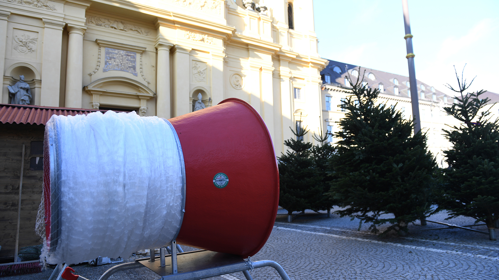 Eine Verpackungsmaschine und Weihnachtsbäume stehen auf dem Odeonsplatz. | picture alliance/dpa