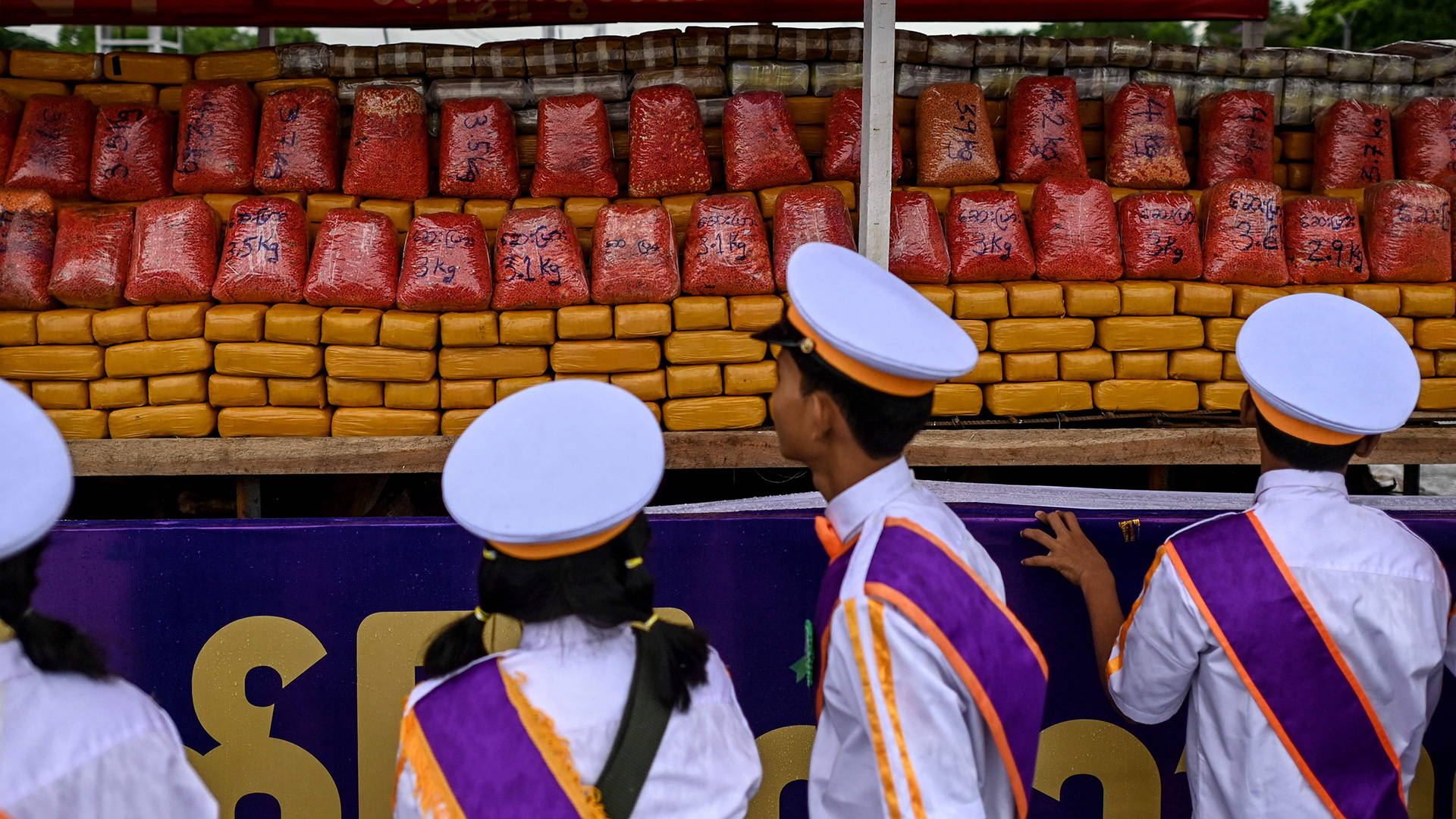 Menschen in Uniform betrachten einen Stapel Pakete. | AFP