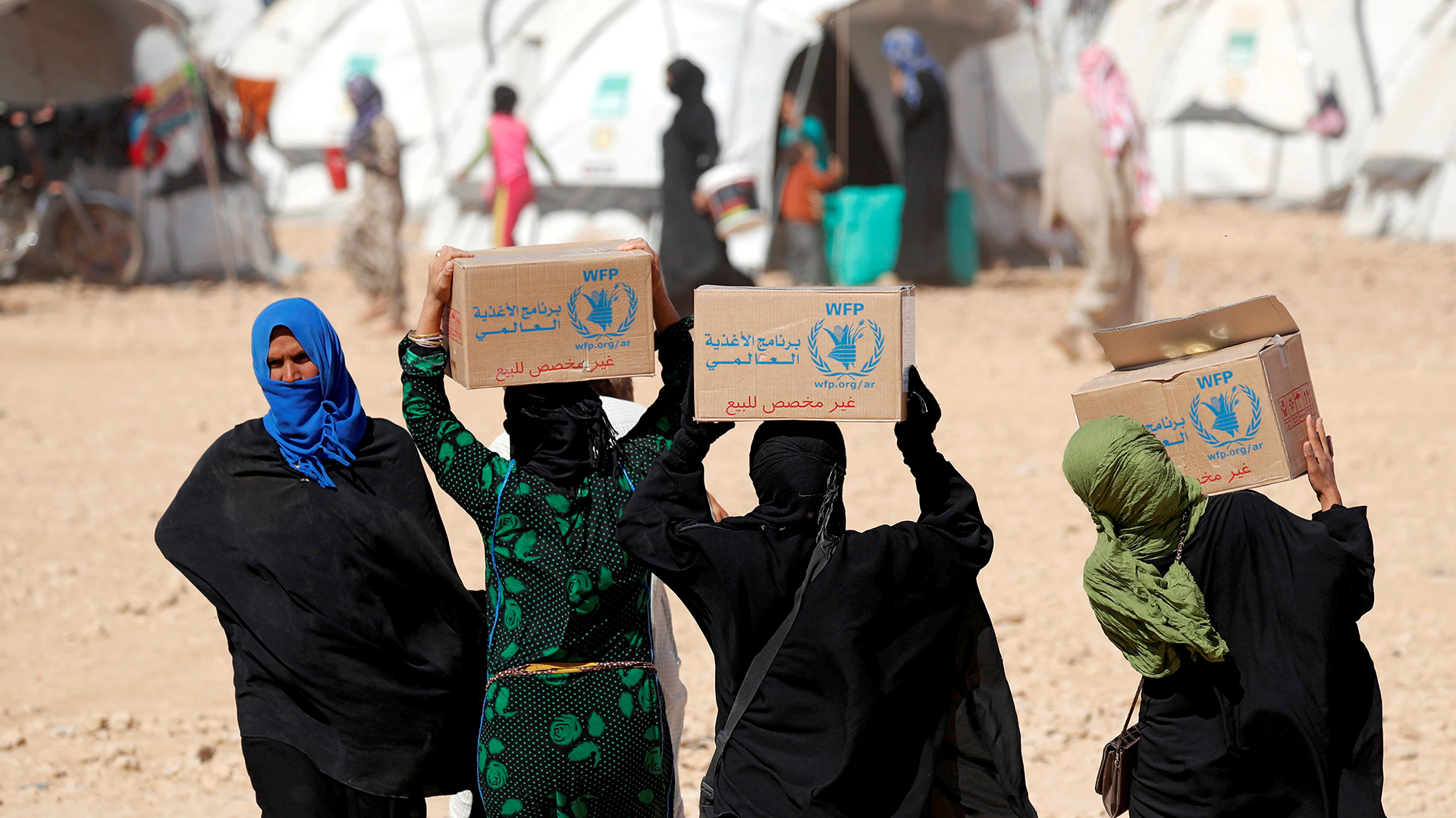 Menschen in einem Flüchtlingslager in Ain Issa, Syrien mit Kisten mit Nahrungsmittelhilfe des Welternährungsprogramms der UNO, Archivbild. | REUTERS