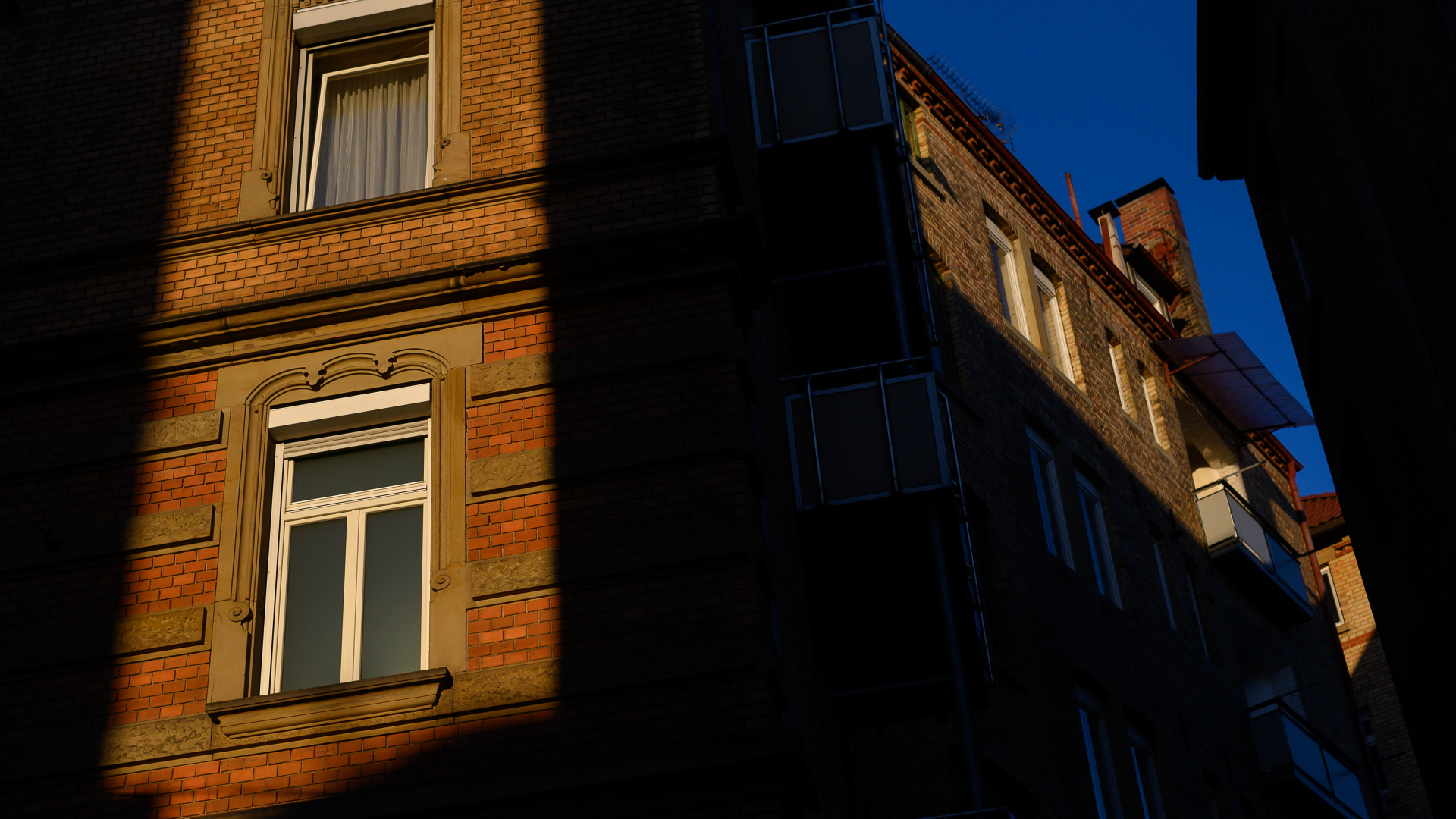 Die Sonne scheint zwischen zwei Häusern auf Fenster von Wohnungen. | dpa