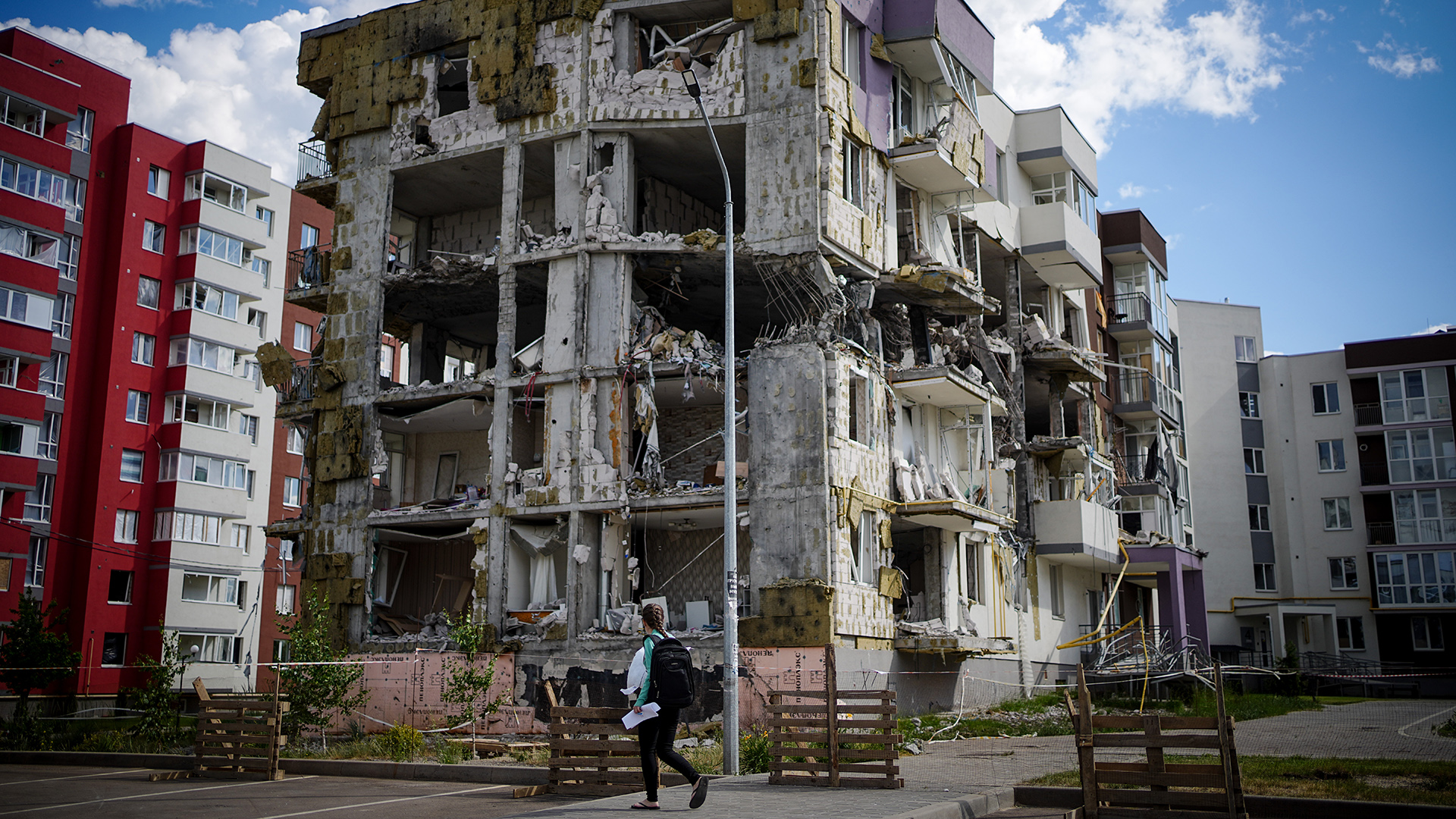 Eine Passantin geht an einem zerstörten Wohnhaus in Butscha bei Kiew vorbei, Ukraine. | dpa