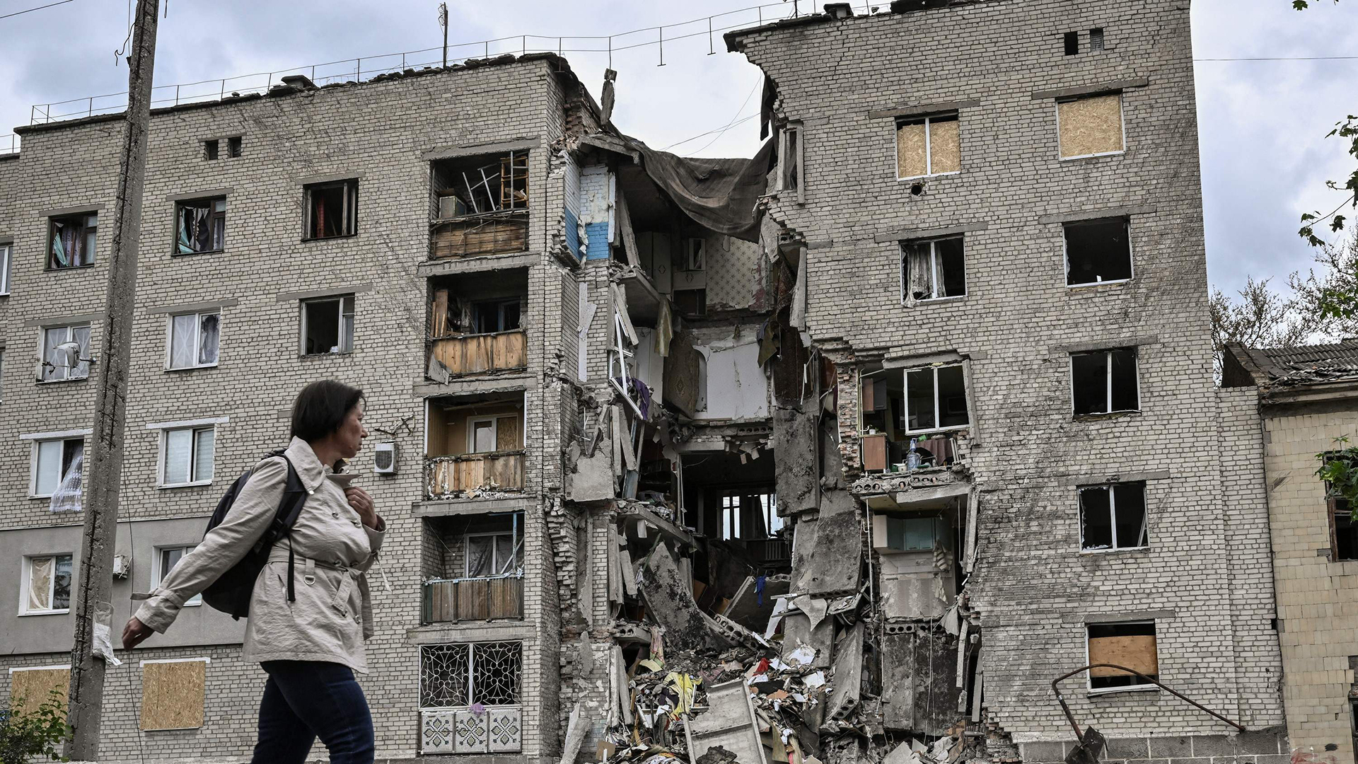 Eine Frau geht an einem zerstörten Wohnhaus in Bakhmut in der ostukrainischen Region Donbass vorbei. | AFP