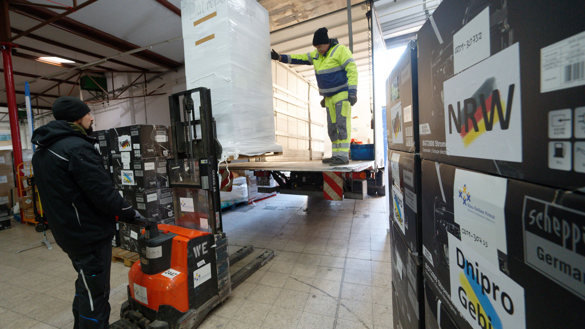 Mitarbeiter laden im Spendenlager der Organisation Blau-Gelbes Kreuz Paletten mit Stromgeneratoren in einen Lastwagen.  | picture alliance/dpa